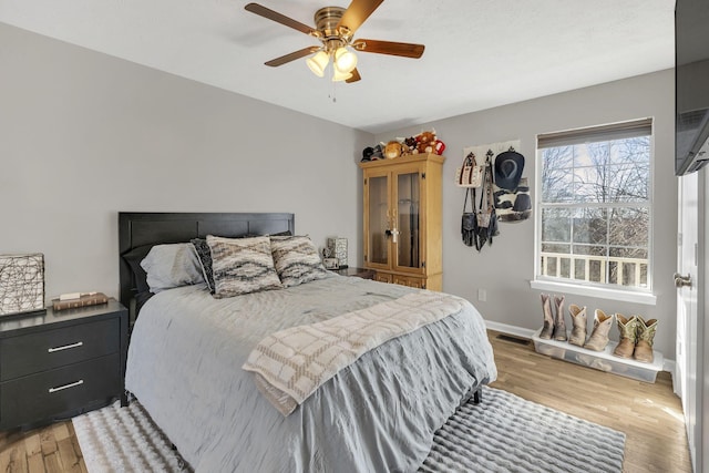 bedroom with light wood finished floors, visible vents, a ceiling fan, and baseboards