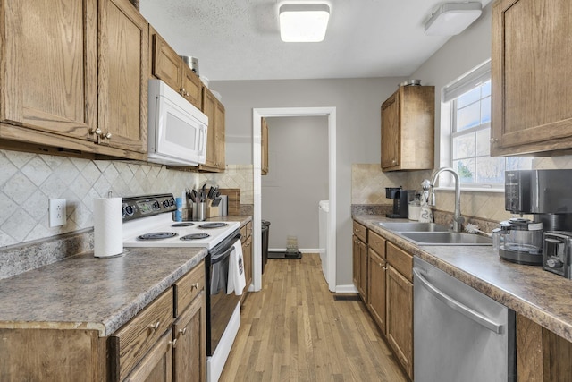 kitchen featuring white microwave, light wood finished floors, dishwasher, range with electric stovetop, and a sink