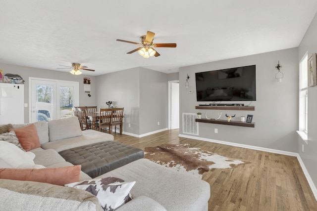 living area with visible vents, baseboards, and wood finished floors