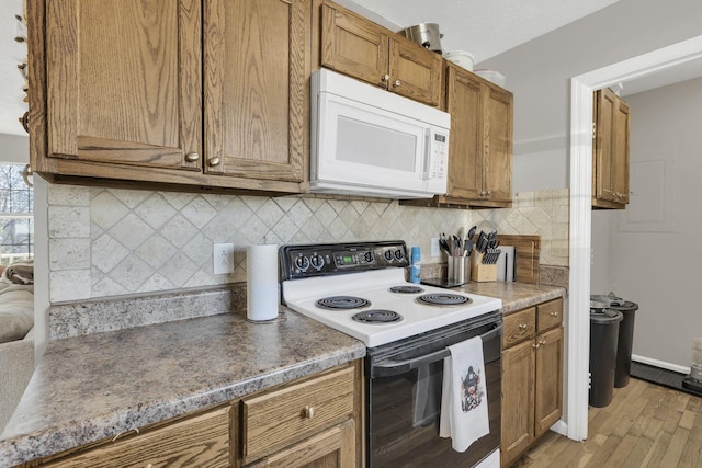 kitchen featuring brown cabinets, light wood-style flooring, electric stove, decorative backsplash, and white microwave