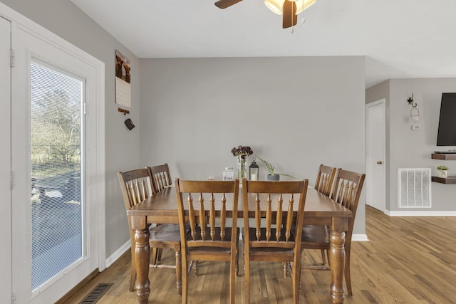 dining room with a ceiling fan, wood finished floors, visible vents, and baseboards