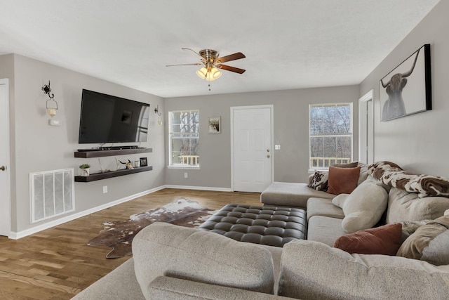 living area featuring visible vents, plenty of natural light, baseboards, and wood finished floors