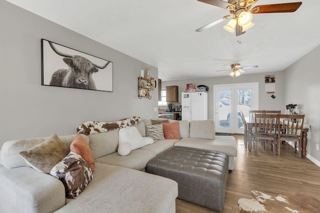 living room with wood finished floors, baseboards, and ceiling fan