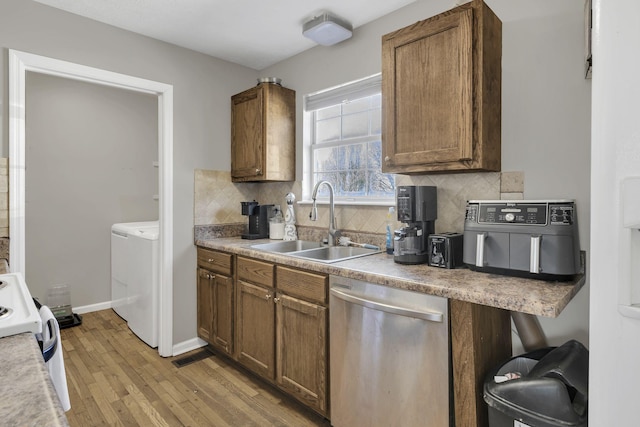 kitchen with baseboards, dishwasher, light wood-type flooring, decorative backsplash, and a sink