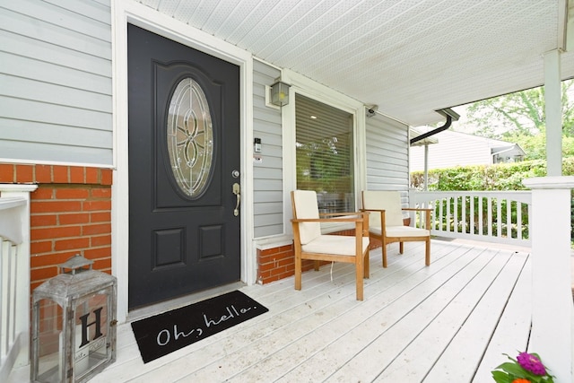 doorway to property with brick siding and covered porch