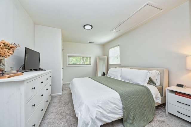 bedroom featuring attic access, baseboards, and light carpet