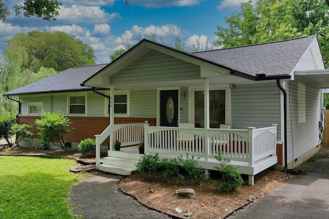 view of front of home featuring crawl space, covered porch, a front yard, and roof with shingles