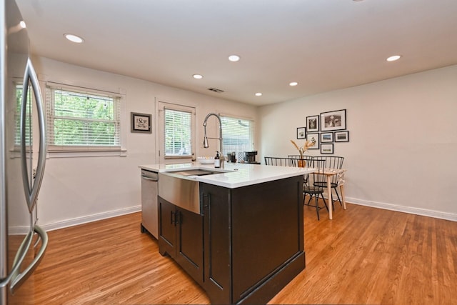 kitchen featuring light countertops, light wood-style flooring, appliances with stainless steel finishes, and a sink