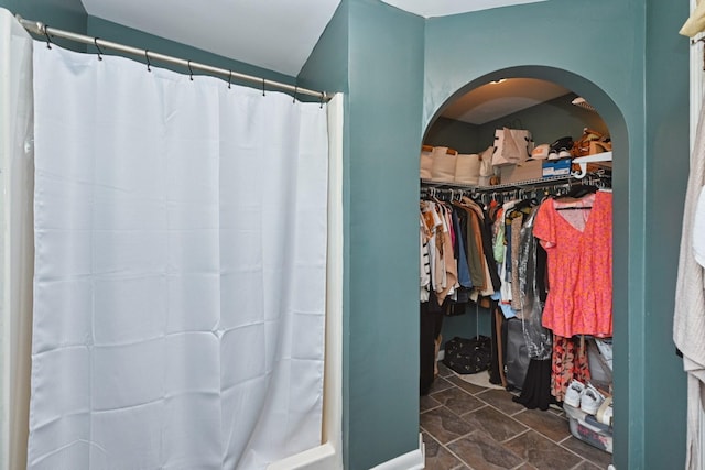 bathroom with a walk in closet and a shower with shower curtain