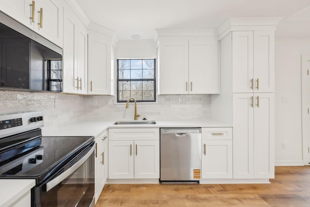 kitchen with a sink, light wood-type flooring, appliances with stainless steel finishes, and white cabinets