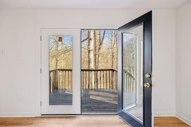 doorway to outside featuring baseboards and wood finished floors