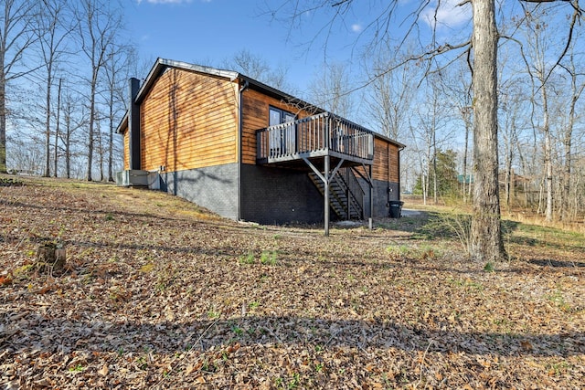 rear view of property with stairway, a chimney, brick siding, and a wooden deck