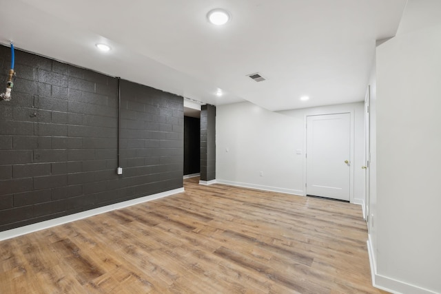 finished basement with visible vents, baseboards, light wood-style flooring, recessed lighting, and an accent wall