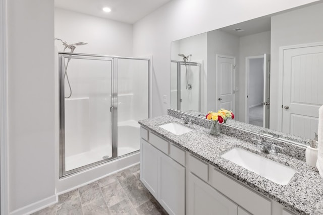 bathroom with a shower stall, double vanity, and a sink