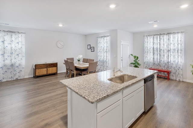 kitchen with visible vents, a sink, stainless steel dishwasher, light wood-style floors, and white cabinets