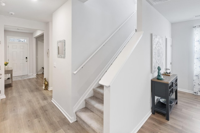 stairs with visible vents, baseboards, and wood finished floors