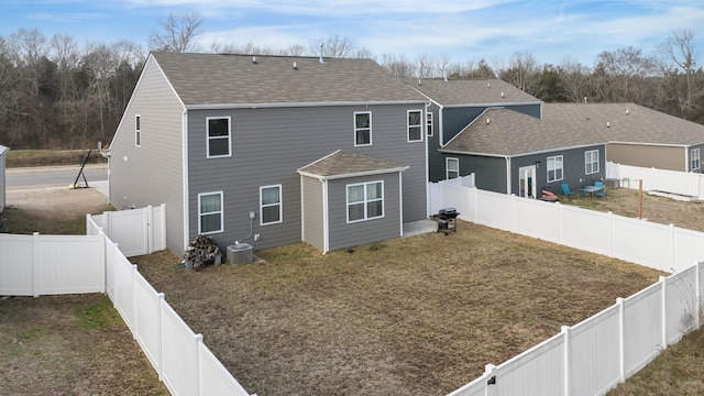 back of property featuring a fenced backyard, a shingled roof, and a yard