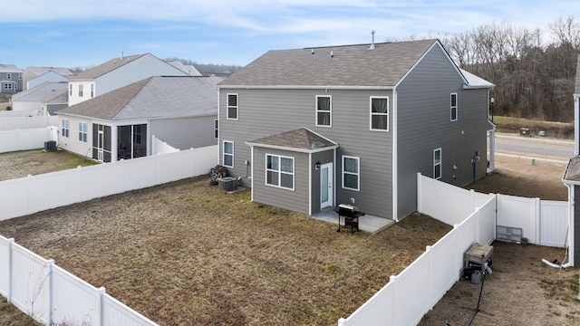 rear view of house with a lawn, central AC, and a fenced backyard