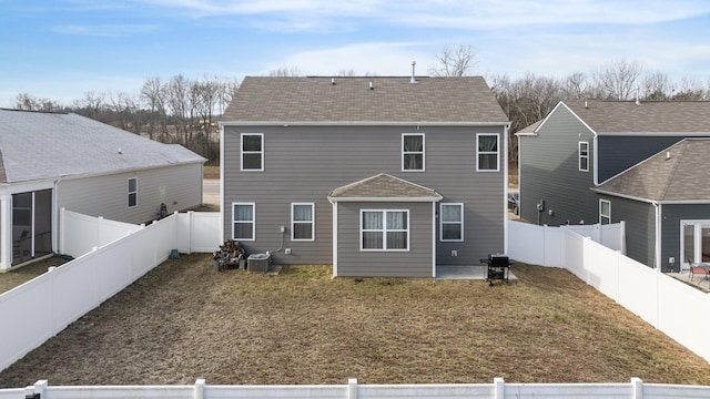 back of property with a patio area, a lawn, a shingled roof, and a fenced backyard