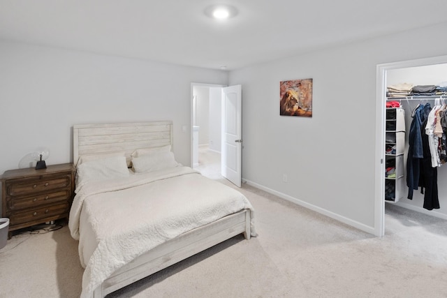 carpeted bedroom featuring a closet, a walk in closet, and baseboards