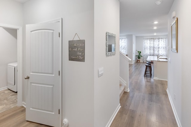 hall with stairs, washer / dryer, wood finished floors, and baseboards