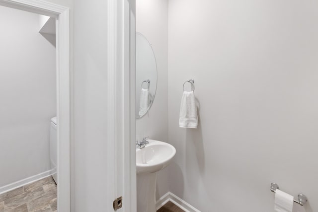 bathroom with stone finish flooring, baseboards, and a sink