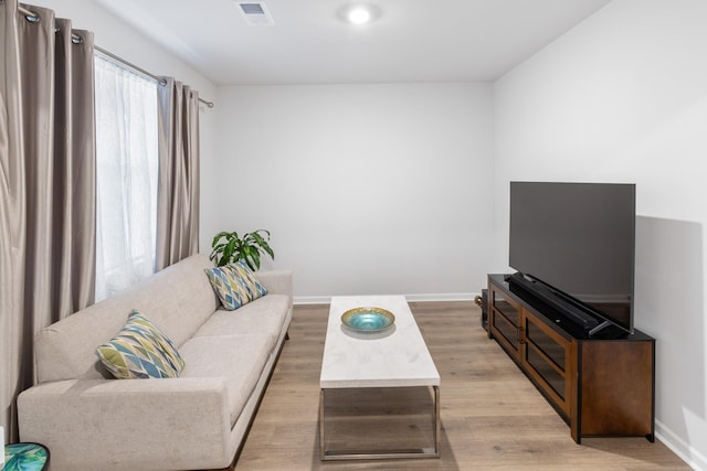 living area with visible vents, light wood-type flooring, and baseboards