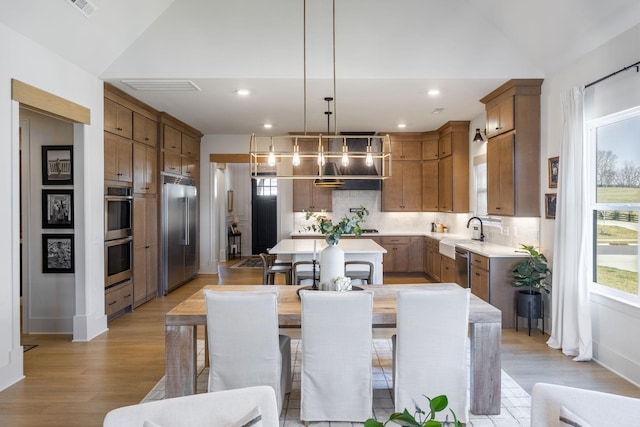 kitchen featuring backsplash, a kitchen island, light wood-style floors, appliances with stainless steel finishes, and light countertops