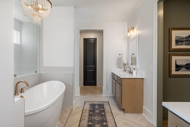 full bath with a notable chandelier, a freestanding bath, and vanity