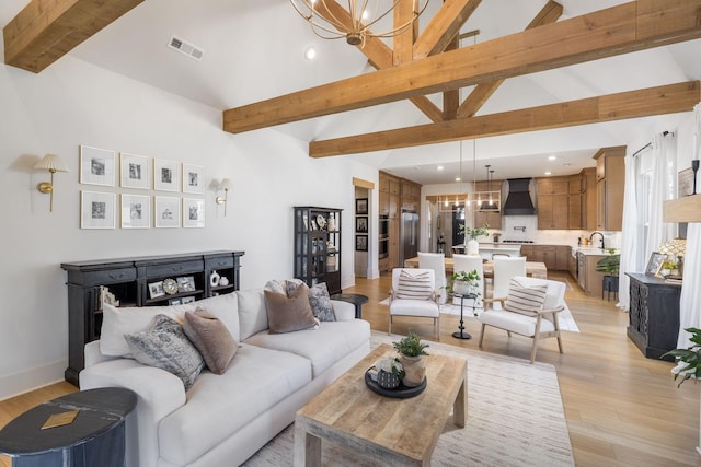 living area featuring visible vents, beam ceiling, high vaulted ceiling, light wood-style floors, and a chandelier