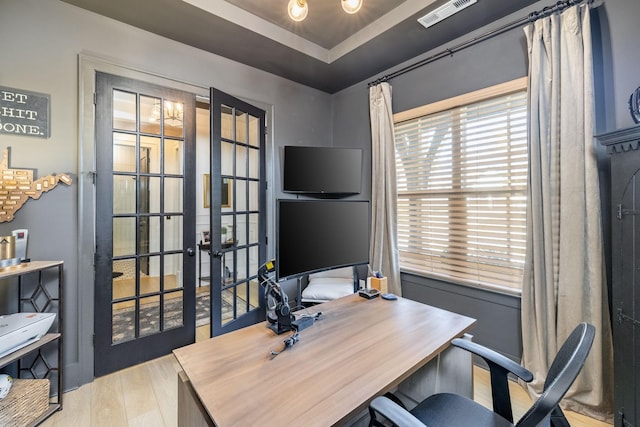 office featuring a tray ceiling, visible vents, wood finished floors, and french doors