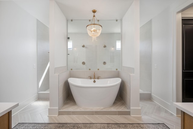 full bathroom with a walk in shower, tile walls, an inviting chandelier, a soaking tub, and vanity