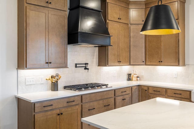 kitchen with custom exhaust hood, backsplash, stainless steel gas cooktop, and light countertops