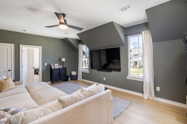 living area with light wood-type flooring, visible vents, baseboards, and ceiling fan