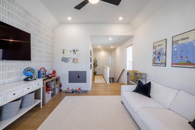 living area featuring wood finished floors, recessed lighting, lofted ceiling, ceiling fan, and an accent wall