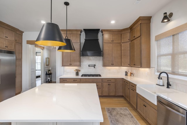 kitchen featuring tasteful backsplash, a center island, light wood-style flooring, custom exhaust hood, and stainless steel appliances