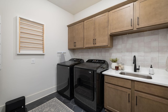 laundry room with dark tile patterned flooring, a sink, cabinet space, separate washer and dryer, and baseboards