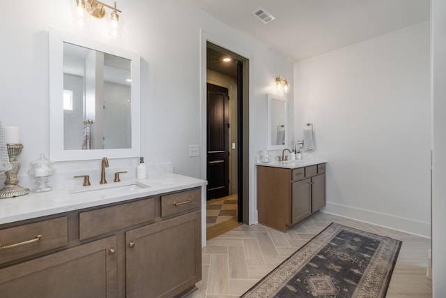 full bathroom featuring two vanities, baseboards, visible vents, and a sink