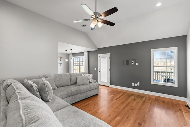 living room featuring visible vents, baseboards, light wood-type flooring, vaulted ceiling, and a ceiling fan