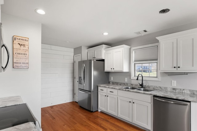 kitchen with visible vents, dark wood-type flooring, a sink, stainless steel appliances, and white cabinets