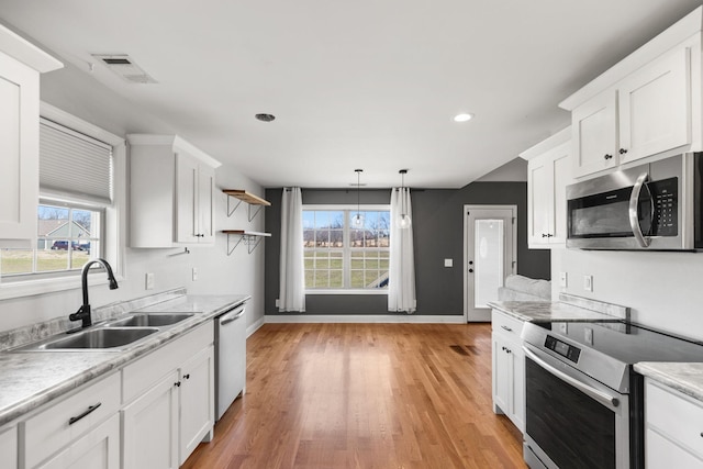 kitchen with visible vents, appliances with stainless steel finishes, white cabinetry, and a sink