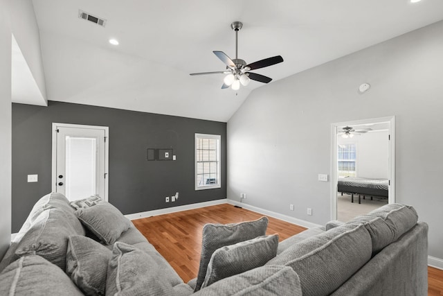 living room featuring visible vents, wood finished floors, baseboards, and vaulted ceiling