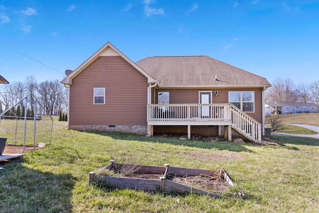 rear view of house featuring a yard, a wooden deck, a vegetable garden, and roof with shingles