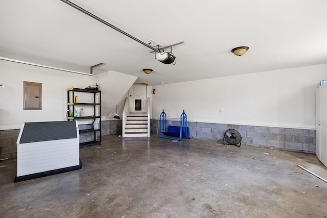 garage with electric panel, a garage door opener, and concrete block wall