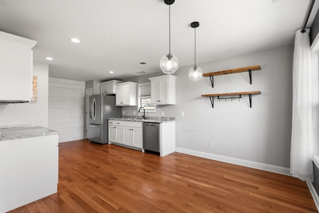 kitchen with wood finished floors, recessed lighting, a sink, white cabinets, and appliances with stainless steel finishes