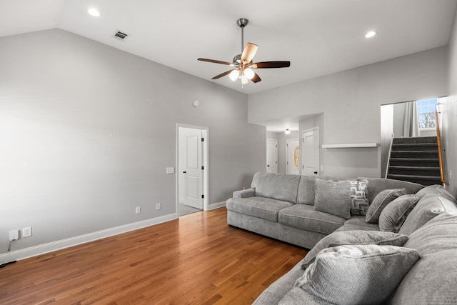 living area featuring stairway, a ceiling fan, wood finished floors, baseboards, and lofted ceiling