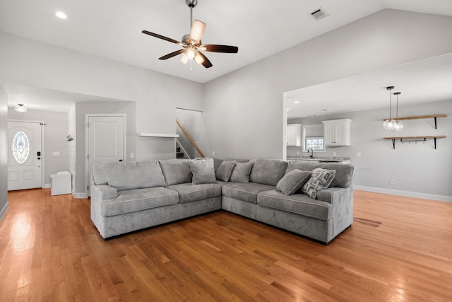 living area with visible vents, light wood-style flooring, stairway, and ceiling fan