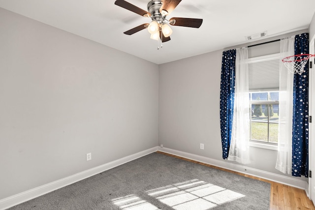 spare room with visible vents, ceiling fan, baseboards, and wood finished floors