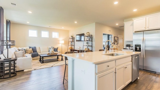 kitchen featuring dark wood finished floors, a sink, stainless steel appliances, a kitchen breakfast bar, and open floor plan