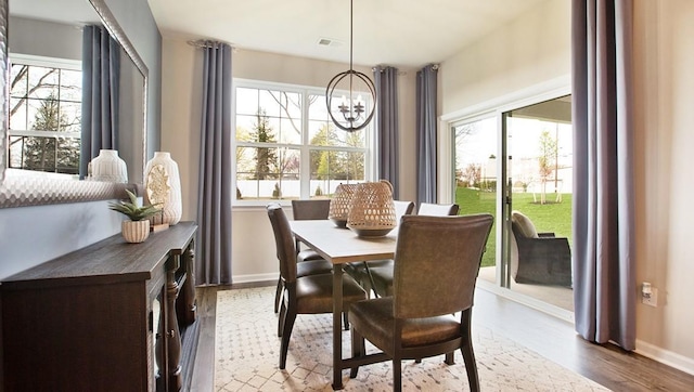 dining area with baseboards, an inviting chandelier, and wood finished floors